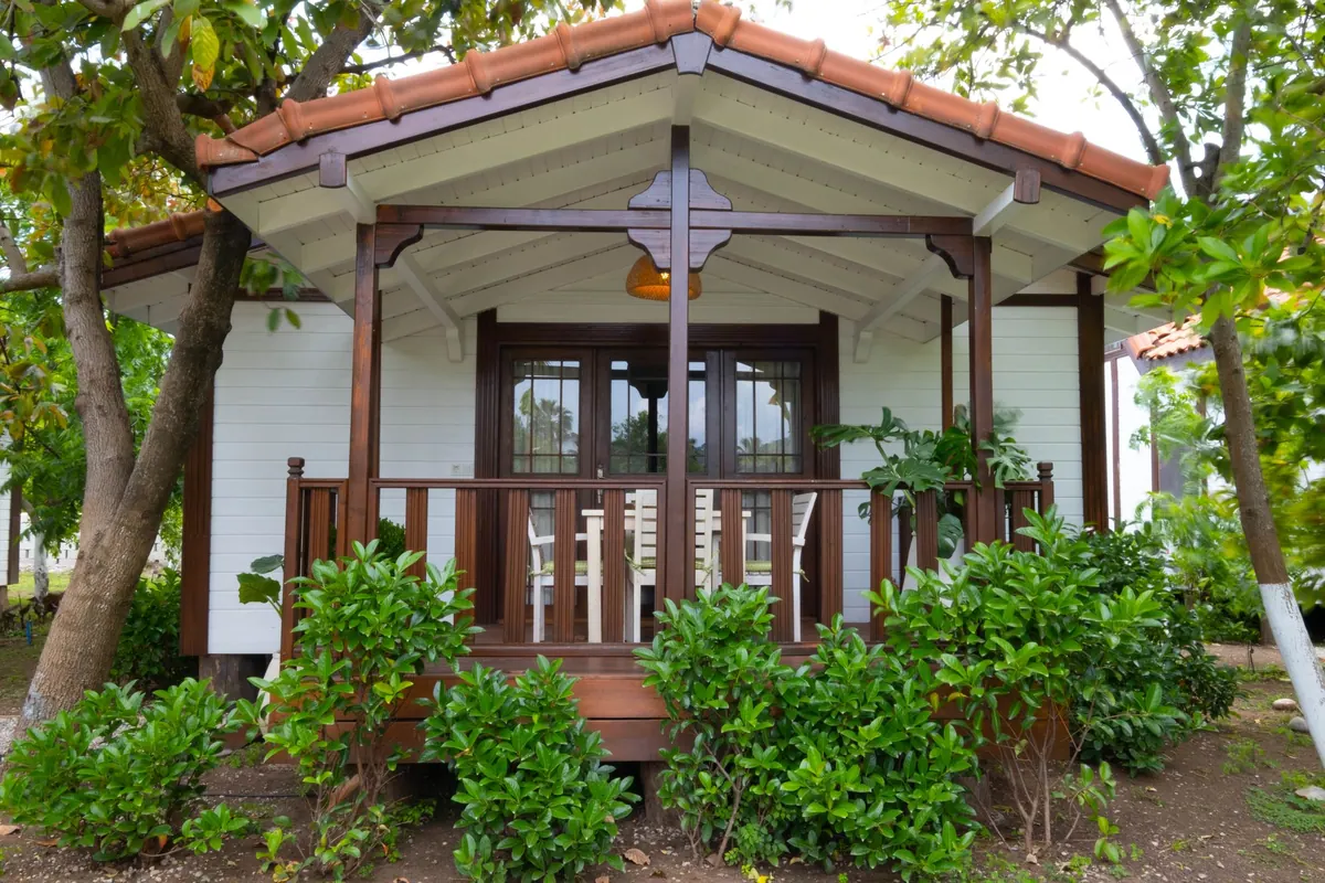 Verandalı ahşap bir ev, önünde yeşillik