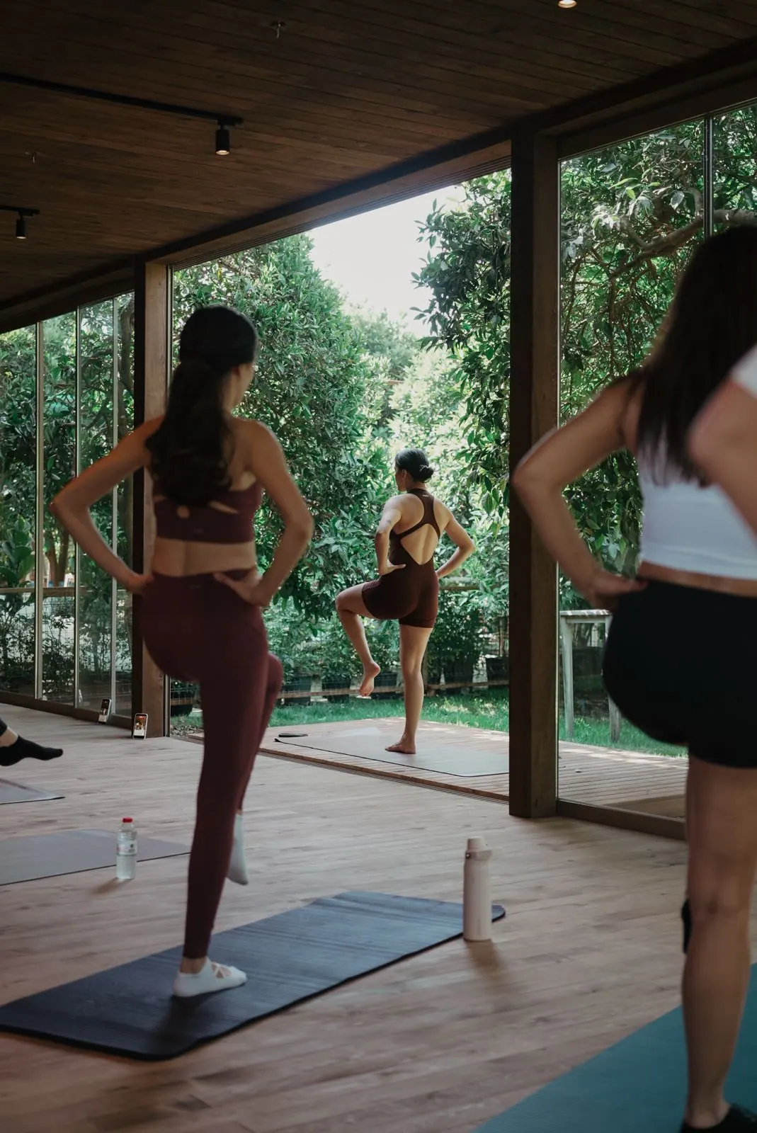 Cam duvarlı ahşap shalada yoga yapan kadınlar